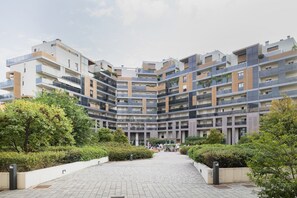 Een modern meerlaags woongebouw met balkons, een centrale binnentuin en omliggend groen.