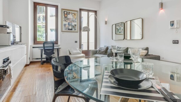 Ein modernes Wohnzimmer mit einem Glastisch, einer Couch und einem Schreibtisch mit Stuhl.