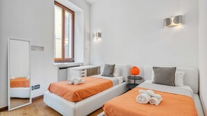 Ein modernes Hotelzimmer mit zwei Betten, einem Schreibtisch, einem kleinen Tisch und einem Spiegel.