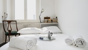 A neatly made bed with white linens, a coffee pot, and rolled towels on a tray. - Easylife - Charming house with terrace (Milano)