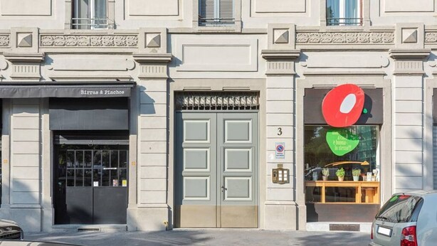 Fachada de edificio con una tienda llamada "Birras & Pinchos" y un letrero circular rojo grande a la derecha.