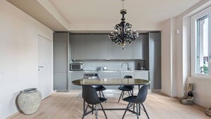 Una cocina moderna con armarios grises, una isla central y una araña.