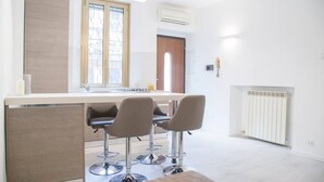 A modern kitchen with a central island, bar stools, and a window with decorative ironwork. - Easylife - Brand, new and fully furnished apt (Milano)