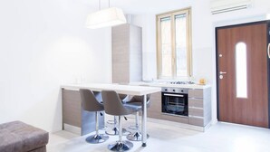 A modern kitchen with a central island, bar stools, a pendant light, and a built-in oven. - Easylife - Brand, new and fully furnished apt (Milano)