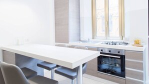 A modern kitchen with a white countertop, stainless steel appliances, and a window with patterned glass. - Easylife - Brand, new and fully furnished apt (Milano)