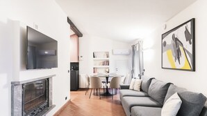 A modern living room with a fireplace, a flat-screen TV, a grey sofa, and a dining area with chairs and a table. - Prestigious apartment Piazza Duomo by Easylife (Milano)