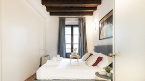 A bedroom with a bed, a bedside table, a window with curtains, a painting on the wall, and a door. - Prestigious apartment Piazza Duomo by Easylife (Milano)