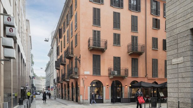 A street with buildings, including a multi-story building with balconies and a sign that reads "AGNELLO". - Prestigious apartment Piazza Duomo by Easylife (Milano)