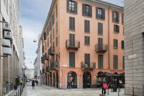 A street with buildings, including a multi-story building with balconies and a sign that reads "AGNELLO".