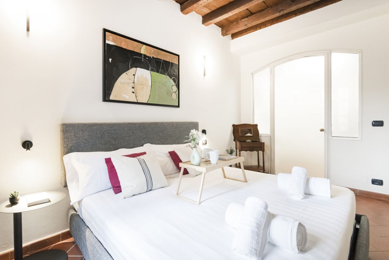 A neatly arranged bedroom with a bed, bedside table, and a painting on the wall.
