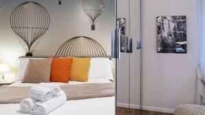 Quarto de hotel com cama, travesseiros, parede com mural e uma moldura com imagem.