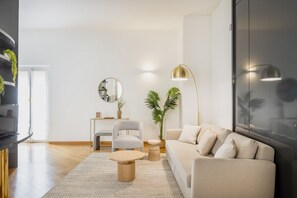 A modern living room with a sofa, armchair, coffee table, and a large mirror.