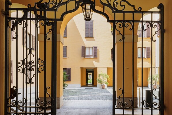 A gated courtyard with a building featuring arched windows and a central door.