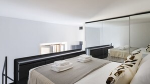 Une chambre d’hôtel moderne avec un grand lit, une table de chevet avec des serviettes, un miroir et une vue sur l’extérieur.