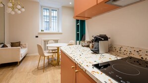 A modern kitchen with a white countertop, a built-in oven, and a dining area with a white table and chairs.