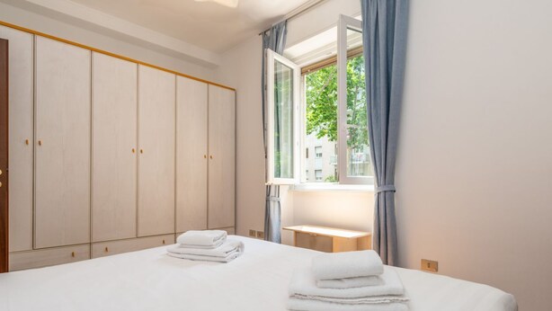Une chambre à coucher avec un lit, une armoire, une fenêtre et une table de chevet.
