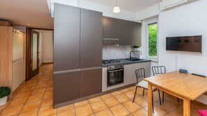 Une cuisine compacte dotée d’appareils électroménagers modernes, un coin repas et une grande fenêtre qui laisse entrer la lumière naturelle.