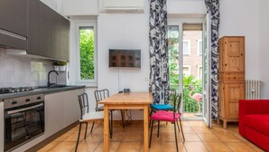 Une cuisine moderne avec un coin repas, un téléviseur fixé au mur et une vue sur l’extérieur.