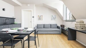 Een moderne keuken met een eetgedeelte, een grijze bank en een loft-stijl plafond.