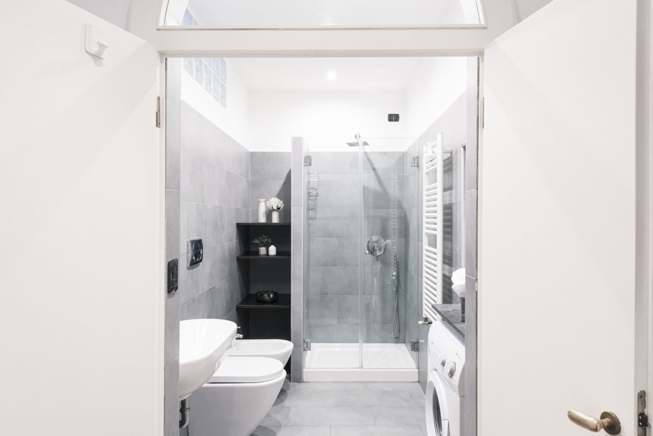 Un bagno moderno con doccia vetrata, lavandino bianco e water.