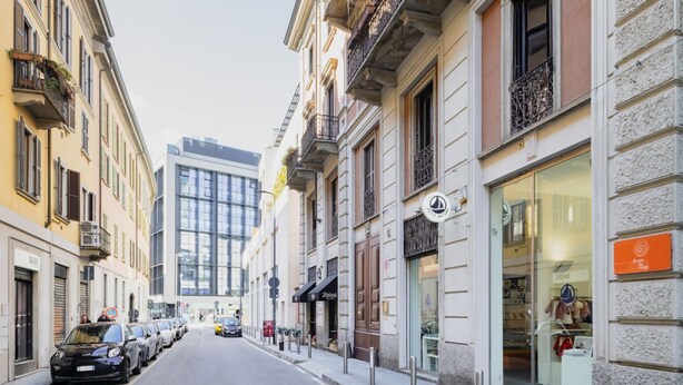 A street lined with historic buildings, some with balconies and storefronts, including a visible shop with a sign. - Easylife - Spacious apartment a few steps from Piazza Gae Aulenti (Milan)