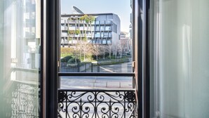 A view from a window with a wrought iron balcony, overlooking a modern building with balconies and a landscaped area. - Easylife - Spacious apartment a few steps from Piazza Gae Aulenti (Milan)