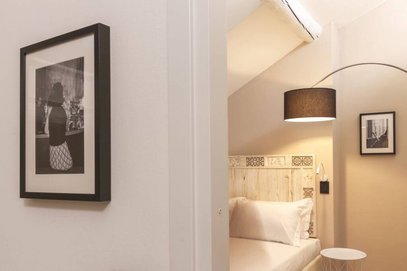 A bedroom with a bed, a bedside table, a lamp, and a framed picture on the wall.