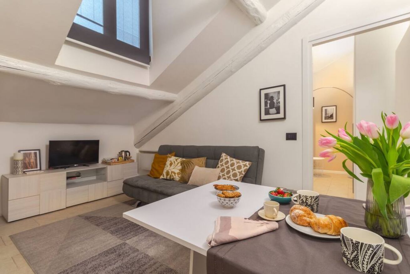 A modern living room with a TV, sofa, and dining table set with food and drinks.