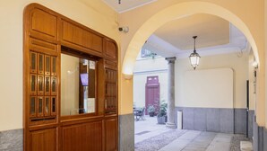 A hallway with a wooden cabinet, an arched doorway, and a tiled floor. - Easylife - Amazing studio in San Babila (Milano)