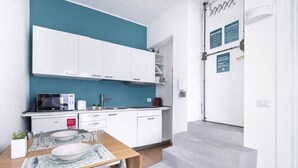 A modern kitchen with white cabinets, a teal backsplash, and a dining area with a wooden table and chairs.