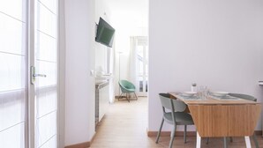 A modern dining area with a wooden table, two chairs, and a television mounted on the wall.