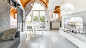Uma sala de estar espaçosa com cozinha moderna, mesa de jantar com cadeiras e uma grande televisão de tela plana.