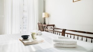 A neatly made bed with white linens, a bedside lamp, and a framed picture on the wall. - Easylife - Bright residence in Sant'Ambrogio (Milano)