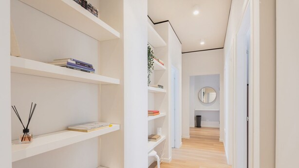 A modern hallway with white shelving units, a round mirror, and a wooden floor. - Easylife - Bright residence in Sant'Ambrogio (Milano)