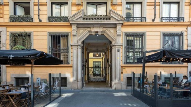 Un edificio con una entrada central flanqueada por zonas de estar al aire libre.