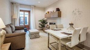 Una sala de estar moderna con un sofá, una mesa de comedor para dos, una mesa de centro y una mesita auxiliar.
