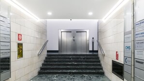Un espace d’ascenseur moderne avec des marches en marbre, une main courante et un panneau indiquant la présence de la banque Allianz.