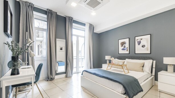 Une chambre moderne avec un grand lit, un bureau avec une chaise et une fenêtre avec des rideaux.