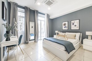 Une chambre moderne avec un grand lit, un bureau avec une chaise et une fenêtre avec des rideaux.