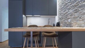 Cocina compacta con una mesa de madera, dos taburetes y un protector de salpicadero de piedra.