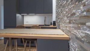 Una cocina moderna con armarios oscuros, una pared de acento de piedra y una mesa de comedor de madera.