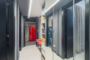 A modern hallway with a red coat rack, a small table with a basket, and a door leading to a bathroom.