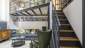 Una sala de estar moderna con un sillón verde, un sofá azul y una escalera con barandilla de metal.