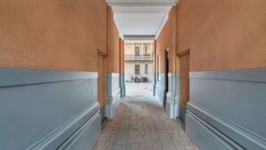 A corridor with beige walls and a tiled floor, leading to a balcony with outdoor seating. - Easylife - Cuddle & relax in the heart of Isola (Milano)