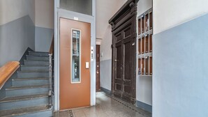 A hallway with a wooden staircase, a brown door, and a large dark wooden door. - Easylife - Cuddle & relax in the heart of Isola (Milano)