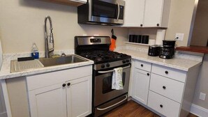 A compact kitchen with white cabinets, a stainless steel stove, a microwave, and a coffee maker. - Cleneay #1, Private 3 Bed near Xavier & Downton (Cincinnati)