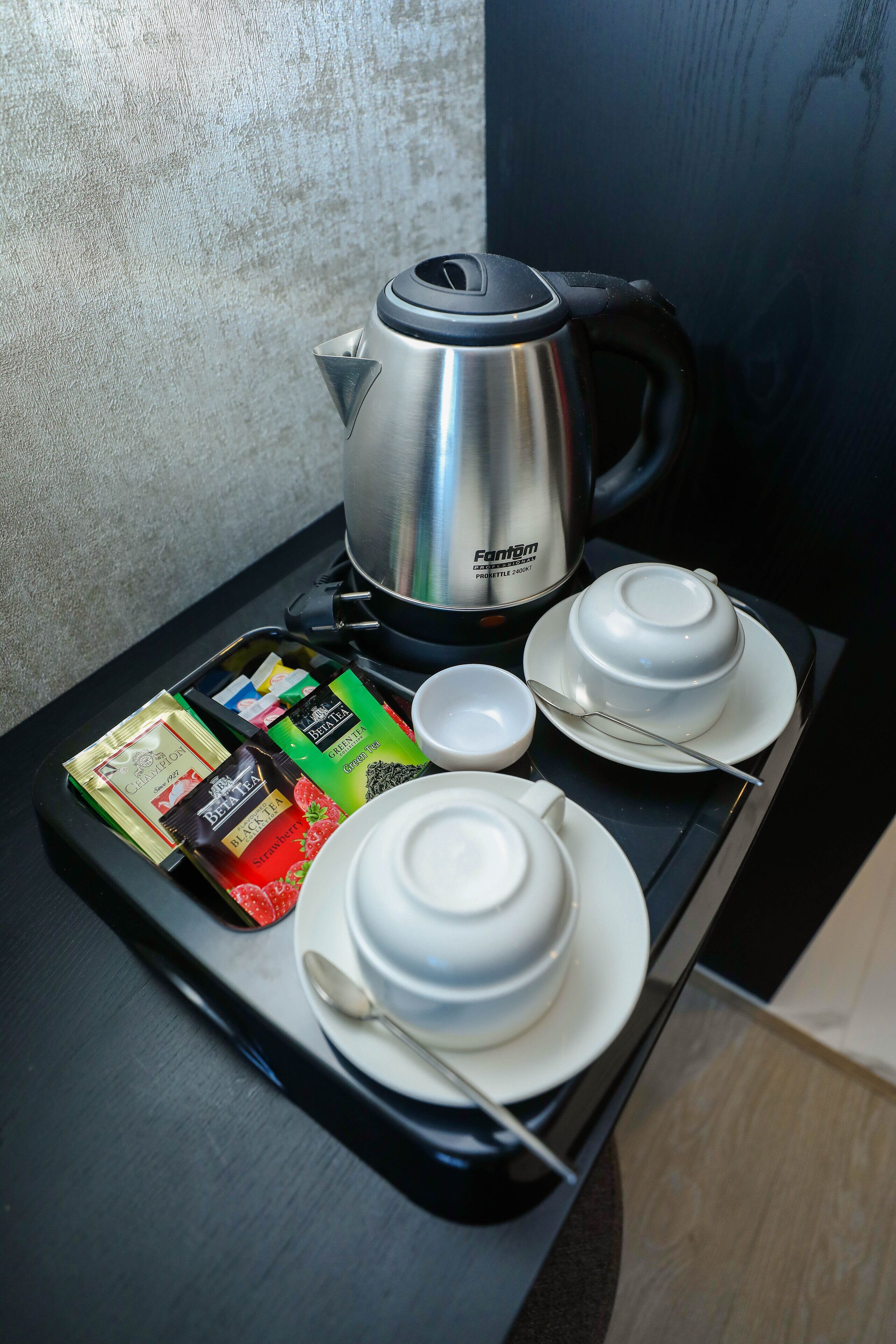 Una bandeja con tetera, teteras, tazas y paquetes de té sobre una mesa.