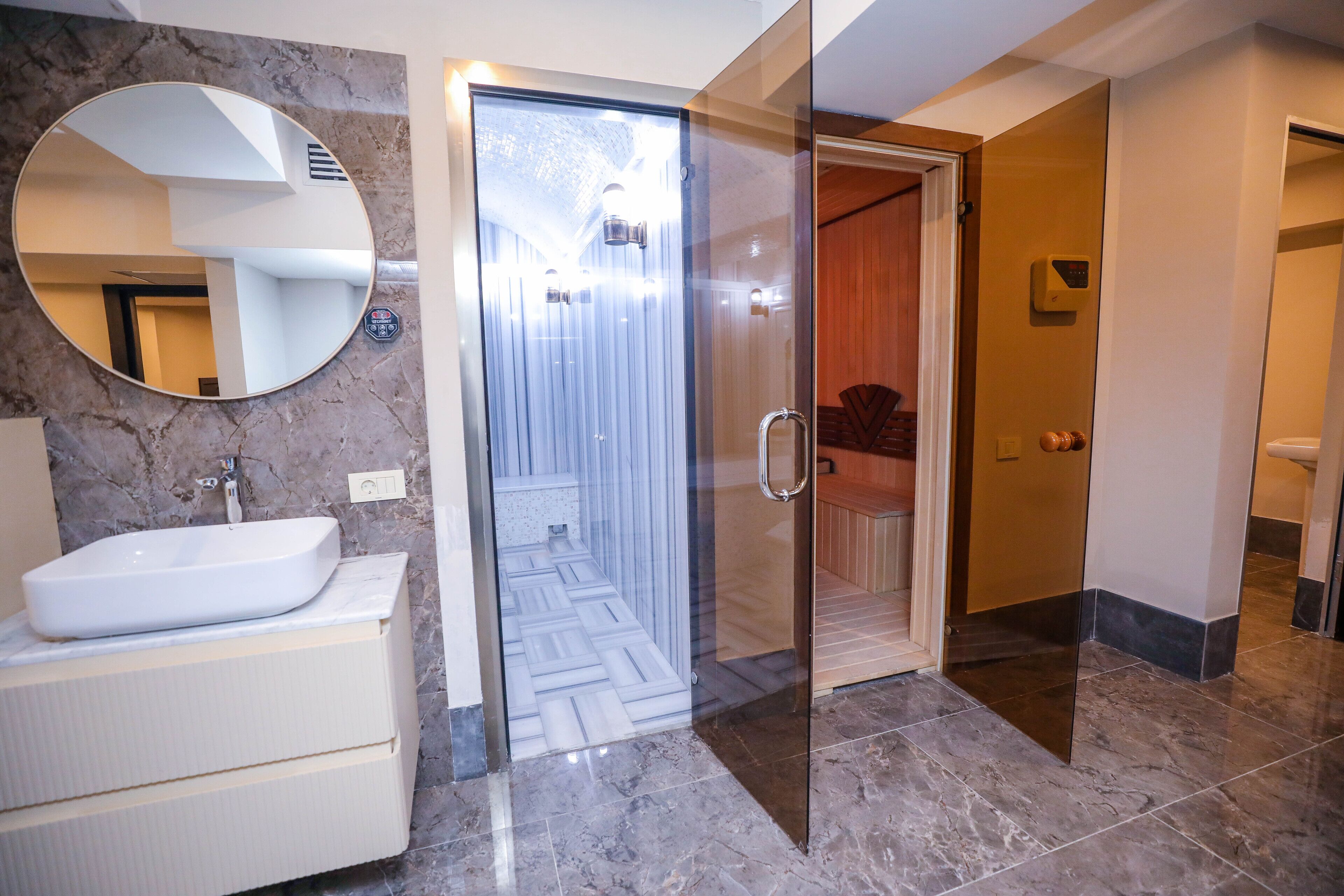 A modern bathroom with a white sink, a large mirror, and a glass shower enclosure.