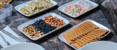 Una mesa de buffet con diversos alimentos, como frutos secos, frutas deshidratadas y pasteles.