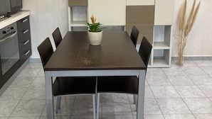 Une cuisine moderne avec une table à manger, des chaises, un four à micro-ondes et une plante en pot.